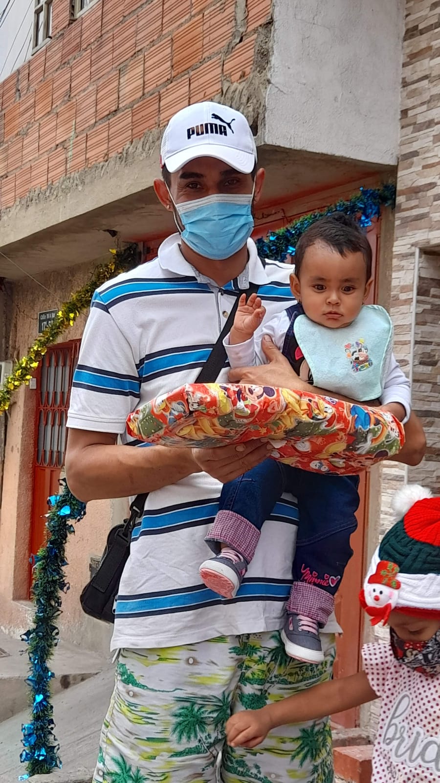 Voluntario de la Fundación cargando a un niño durante la entrega de regalos de Navidad en Ciudad Bolívar, Bogotá